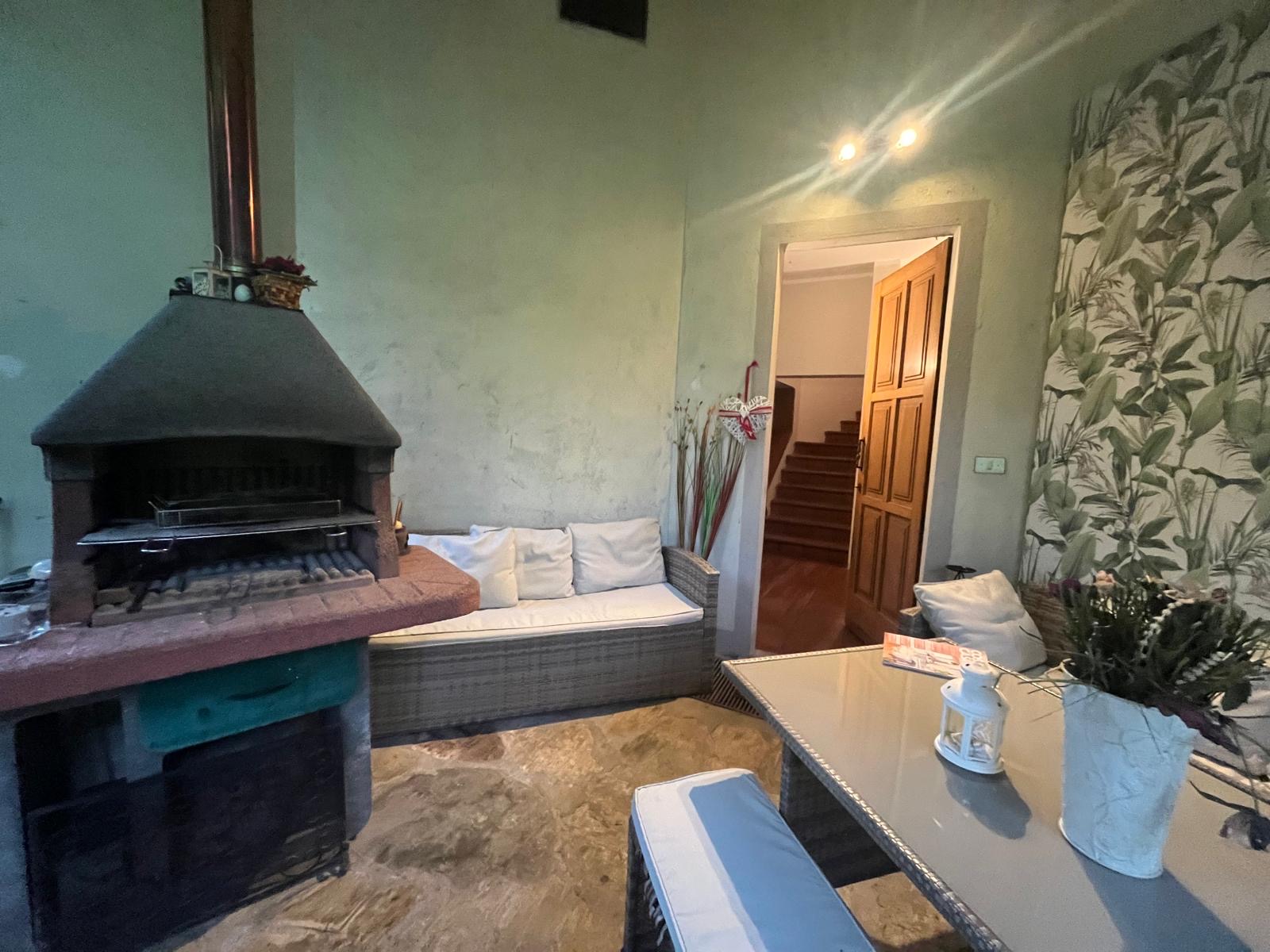 Portico con barbecue in muratura, divano e tavolo da esterno