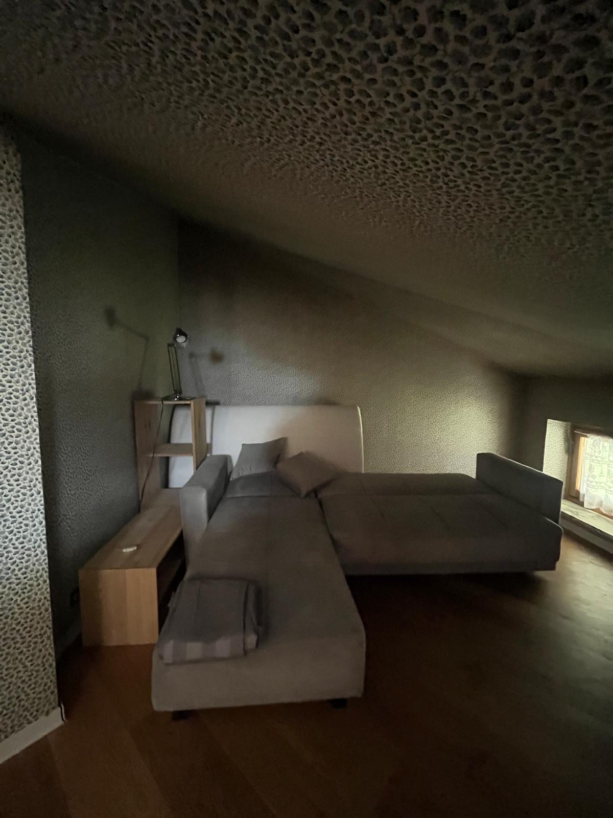 Mansarda con letto e divano letto sotto il tetto spiovente