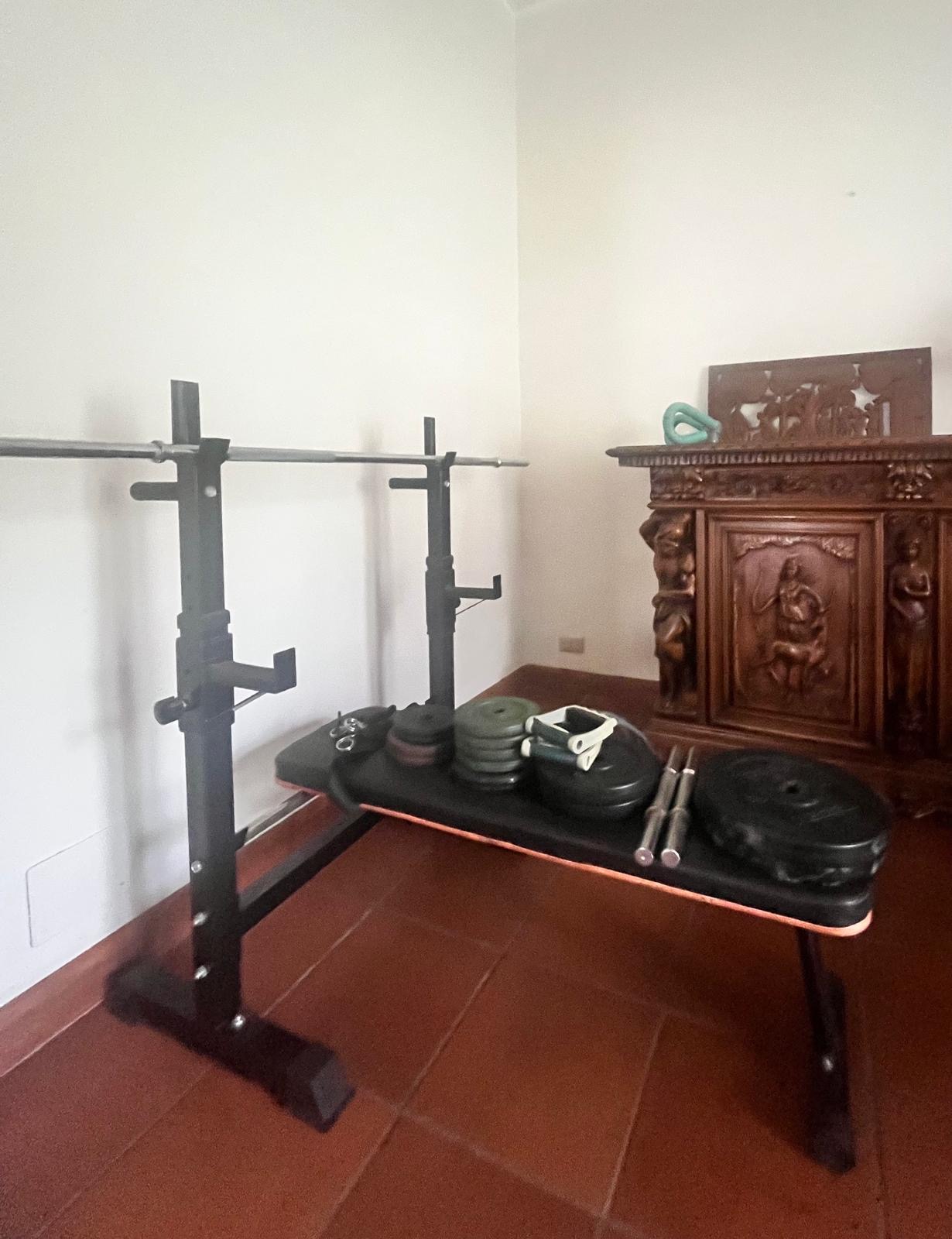 Angolo fitness con panca, bilanciere e pesi